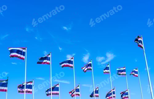 Preview: Many of Thailand flag waving on top of flagpole against blue sky. Thai flag was drawn to top
