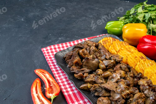 Preview: bottom view chicken liver fry with potato on platter colored bell peppers coriander on table