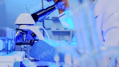 Preview: Asian scientist doing some research and looking through a microscope in laboratory.