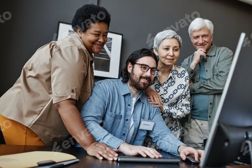 Preview: Diverse group of smiling senior people in computer class for elderly