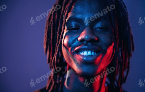 Preview: Smiling, positive facial expression. African American guy is studio with neon lighting