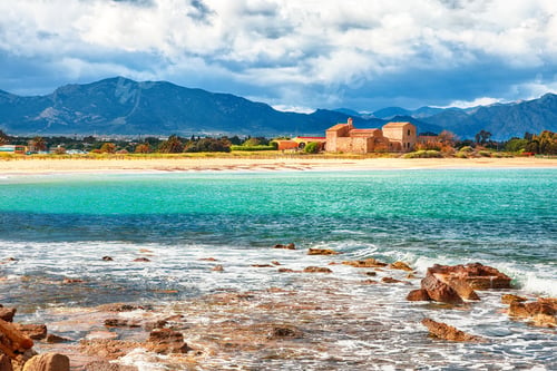 Preview: The Nora bay and beach, the medieval Sant'Efisio church near the shore and mountains