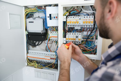 Preview: Electrician repairing fuse box with screwdriver indoors, closeup
