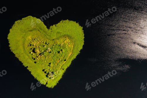 Preview: Love island on a lake in Europe, a Green heart-shaped Island on a dark lake with a sparkle from the