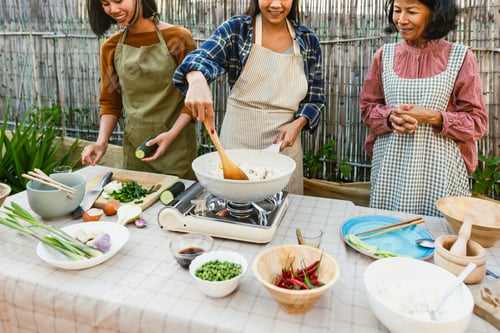 Preview: Southeast asian mother with her daughters having fun cooking Thai food recipe at house patio