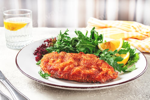 Preview: Milanese chicken, Crispy breaded chicken served, with fresh herbs, and lemon wedges,