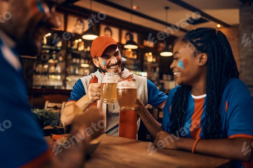 Preview: Happy sports fan toasting with his friends while drinking beer in bar.