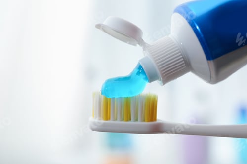 Preview: Applying toothpaste on brush against blurred background, closeup