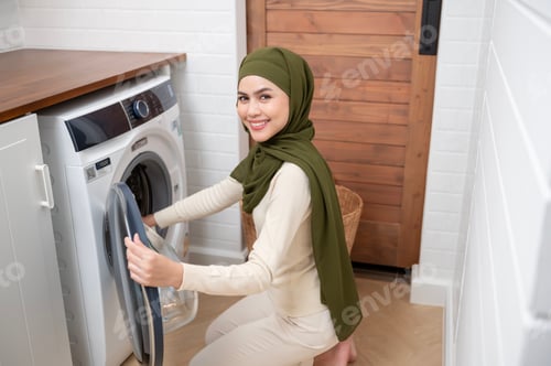 Preview: Muslim woman wearing hijab doing laundry in home