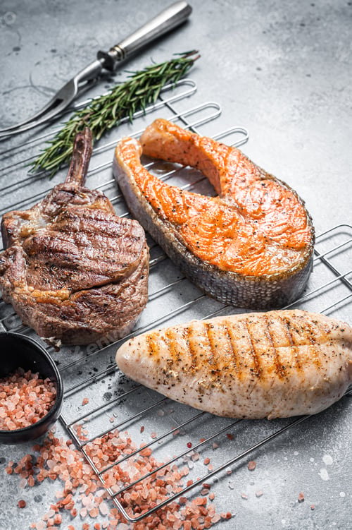 Preview: Set of bbq grilled meat steaks salmon, beef and turkey on a grill. Gray background. Top view