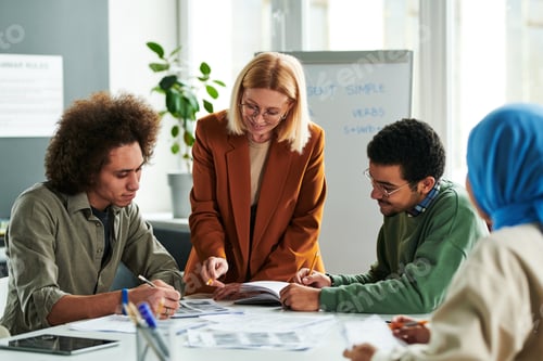 Preview: Successful teacher consulting one of students at lesson