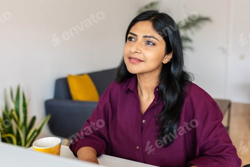 Preview: Thoughtful young indian woman working on laptop at home.
