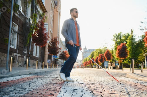 Preview: Young handsome blinded man walking with stick in town