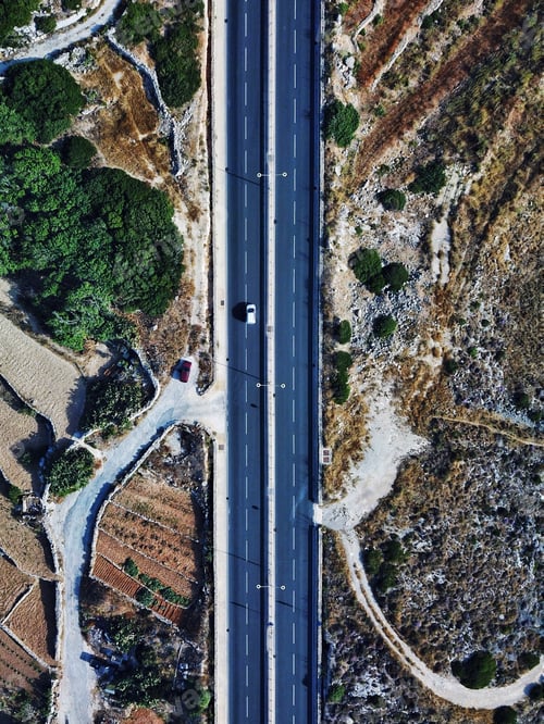Preview: Aerial: A high angle view of a two way road surrounded by rural area.