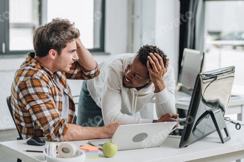 Preview: two shocked multicultural programmers looking at each other and holding hands near heads