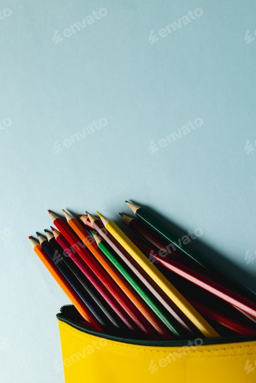 Preview: Vertical composition of colorful crayons in yellow case on mint surface with copy space