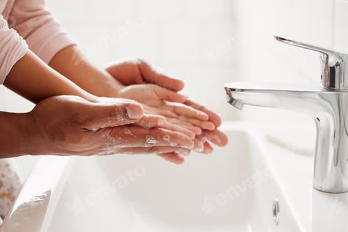 Preview: An unknown mixed race father and daughter washing their hands together in a bathroom at home. Unre