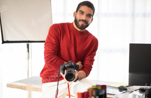 Preview: Positive young guy professional photographer posing at his workplace