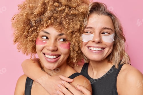 Preview: Positive two women friends embrace each other with love appply hydrogel patches under eyes smile bro