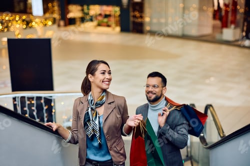 Preview: Young smiling couple on escalator in a shopping mall.