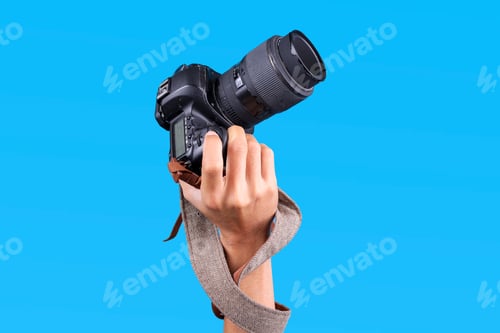 Preview: Person Holds Camera With a Large Telephoto Lens, Pointed Upwards Against a Blue Background