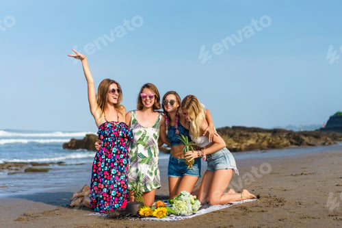 Preview: group of happy young women with various fruits spending time on beach