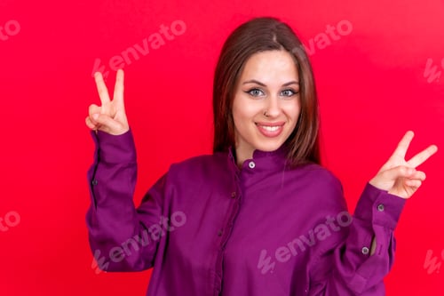 Preview: Smiling Woman Showing Peace Sign Against Red Background
