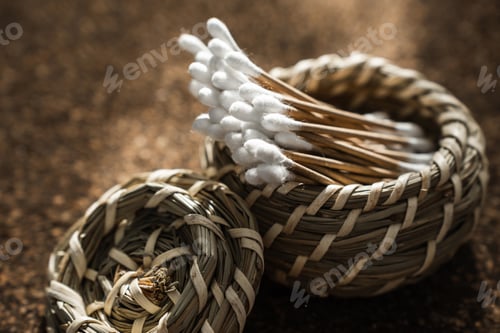 Preview: Wooden Cotton Swabs in Woven Basket on Cork Surface