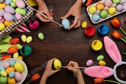 Preview: Stylish background with colorful easter eggs pastel colors on wooden background. Hands holding paint