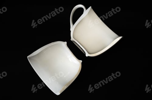 Preview: Closeup of a white coffee cup broken in half isolated on a black background