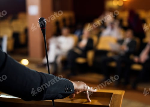 Preview: Hand of a Business Woman at a Podium with a Micrphpne