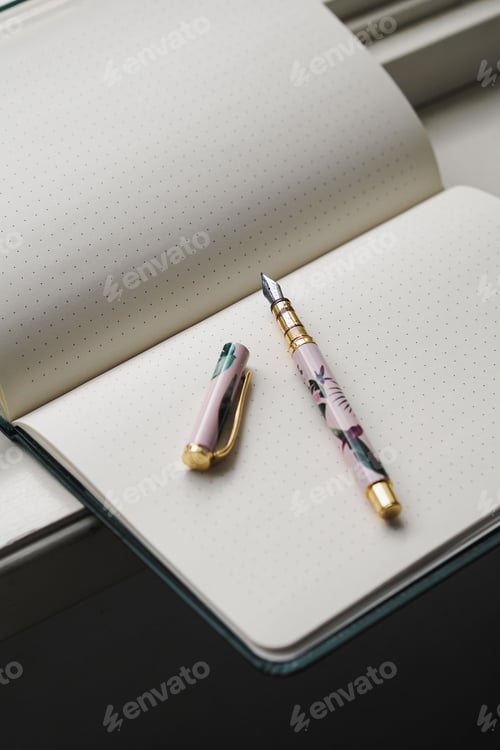 Preview: Open notebook with blank pages and a pen on a windowsill