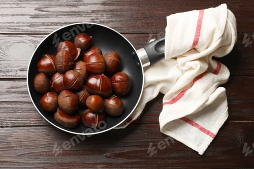 Preview: Roasted edible sweet chestnuts in frying pan on wooden table, top view