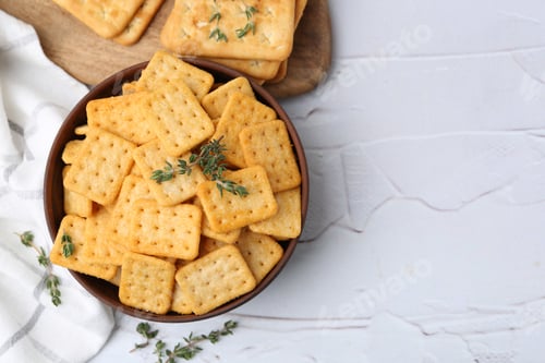 Preview: Tasty salty crackers and thyme on white textured table, flat lay. Space for text