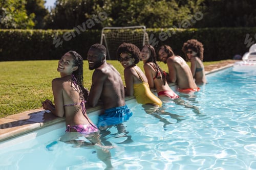 Preview: Diverse group of friends smiling and leaning on the poolside