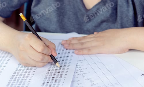 Vista previa: Students hand holding pencil writing selected choice on answer sheets