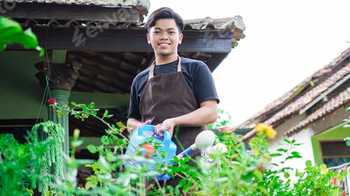 Preview: Asian man taking care watering flower at home garden