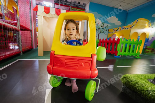 Preview: Kids playing at indoor play center playground , girl in toy car.