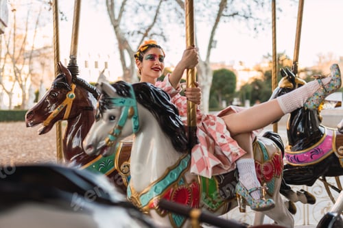 Preview: Sensual street performer sitting on horse of merry-go-round