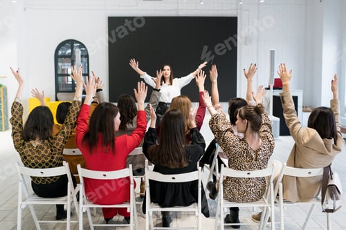 Preview: A group of people sitting with their hands up in seminar.