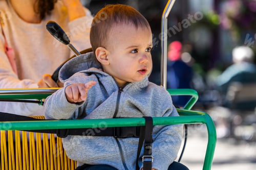 Preview: Adorable Baby Enjoying a Fun Bicycle Ride Outdoors on a Sunny Day with Family