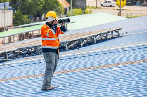 Preview: professional camera man working in dangerous workplace photograph at industry workplace outdoors