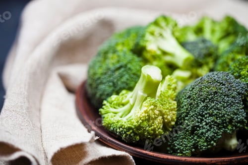 Preview: Fresh green organic broccoli in brown plate and linen napkin.