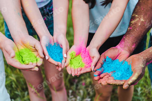 Preview: cropped view of multicultural friends holding colorful holi paints in hands