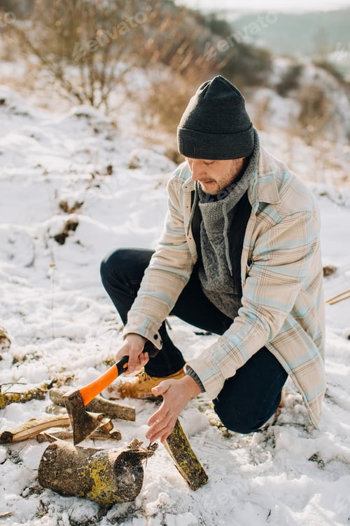 Preview: Man chopping firewood with axe in snowy nature