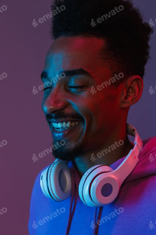 Preview: Portrait of happy african american man in colorful hoodie posing with headphones