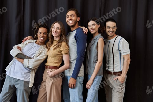 Preview: group photo of successful multiethnic team smiling at camera on black backdrop in modern office