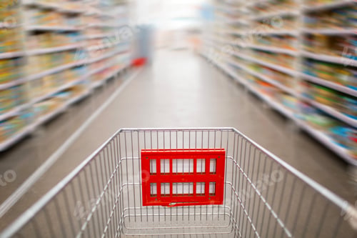Preview: Grocery cart and shelves with products in the store. Motion blur.