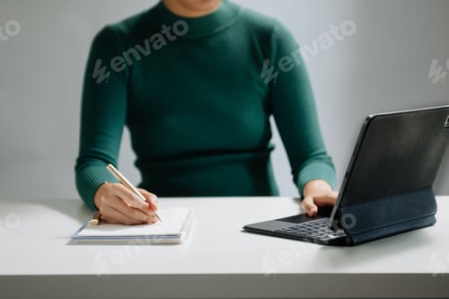 Preview: Close-up view of young professional businessman writing his idea concepts on notebook while working