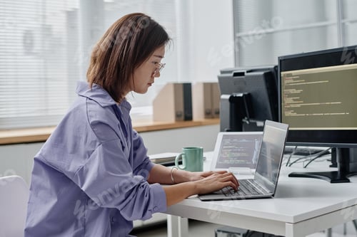 Preview: Young woman typing codes on laptop